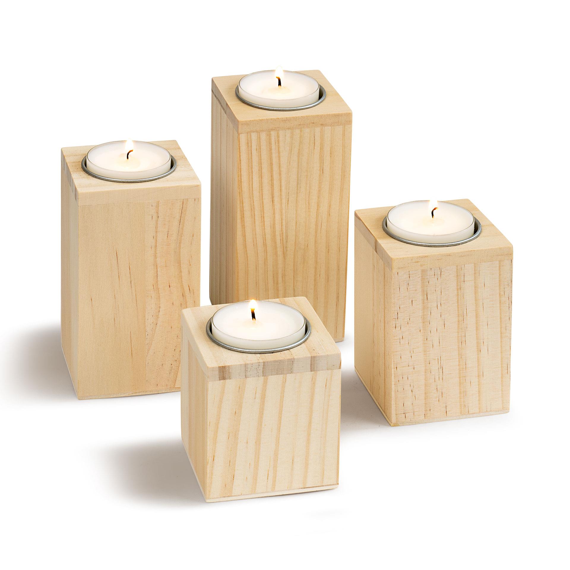 Vier Teelichthalter aus Holz in verschiedenen Höhen mit eingesetzten Kerzen, ideal zum Bemalen und Dekorieren