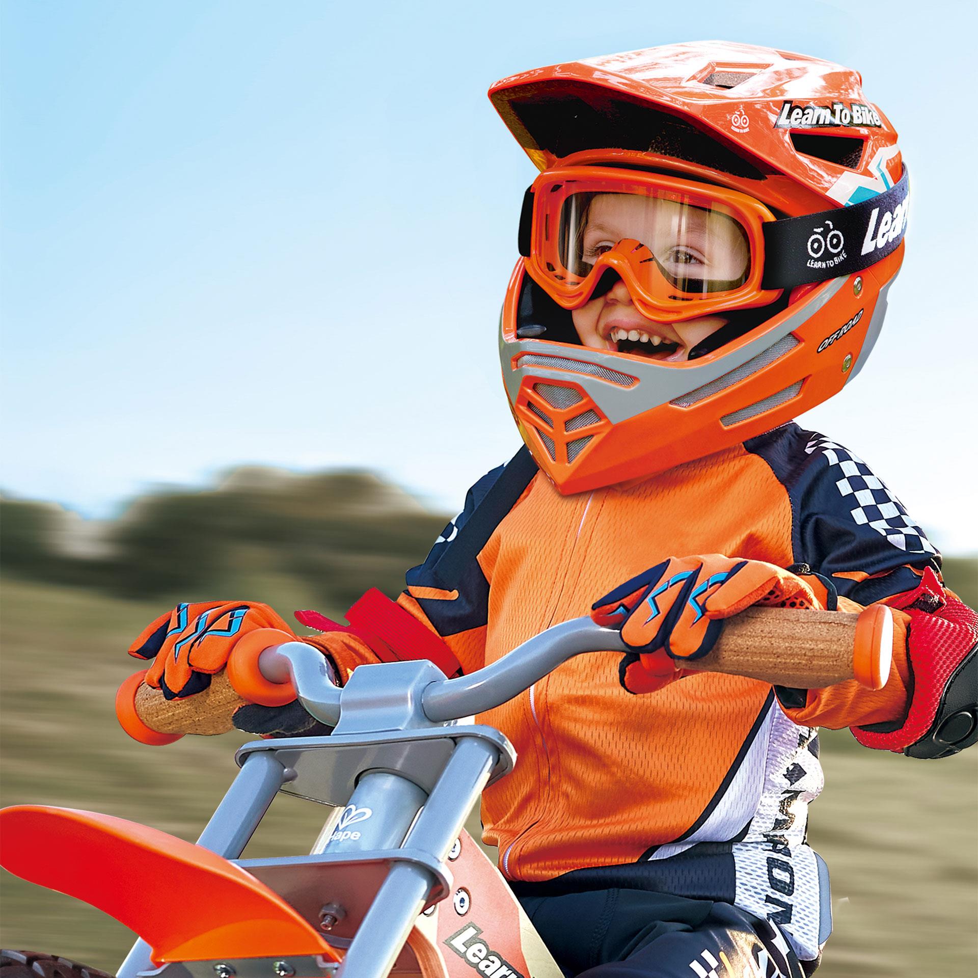 Oranger Kinder-Bikerhelm im Offroad-Stil mit grossen Belüftungsöffnungen und Visier, seitlich «Learn To Bike»-Beschriftung