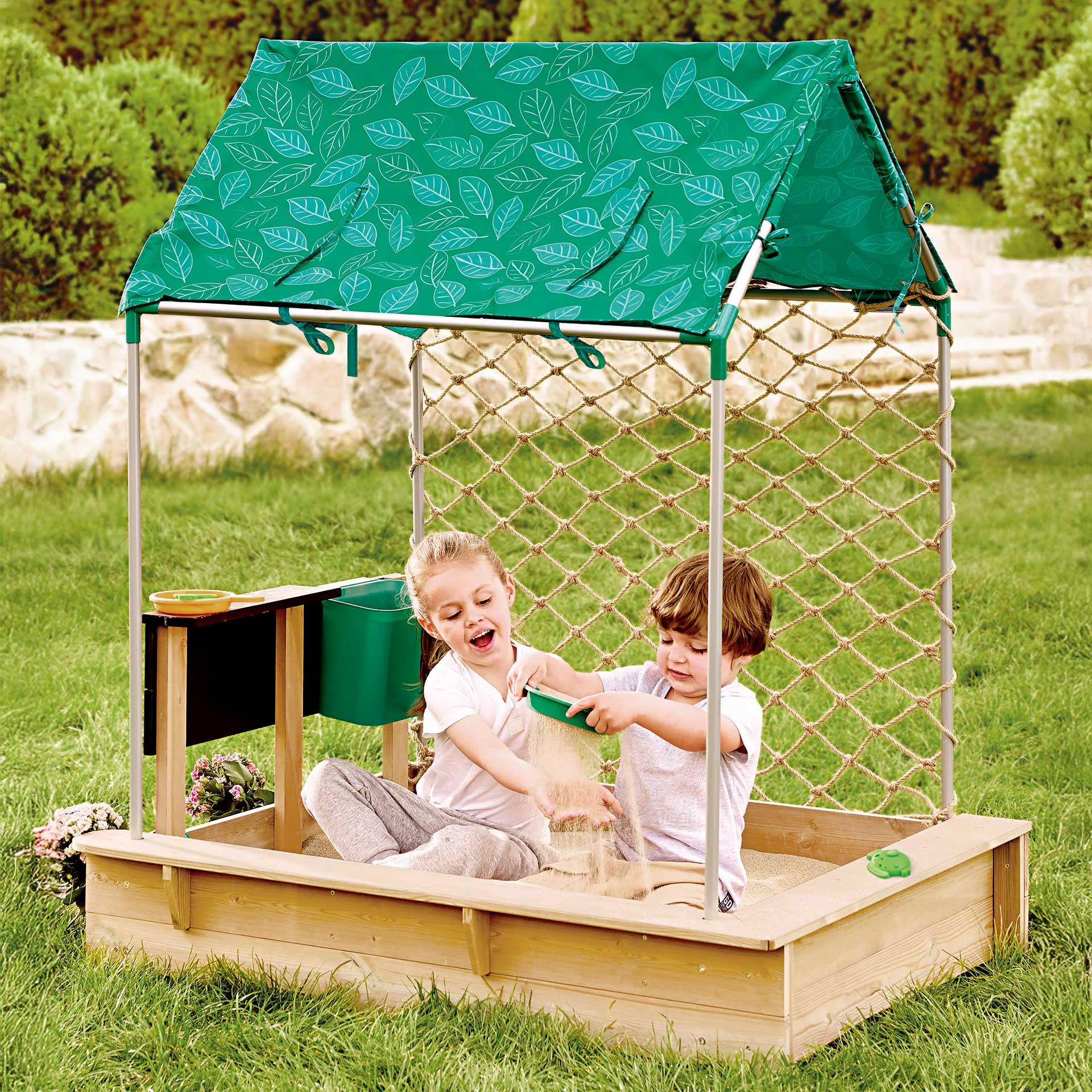 Sandkastenhaus mit grünem Dach, Netzwand und Tafel; Zubehör wie Töpfe und Sandspielzeug