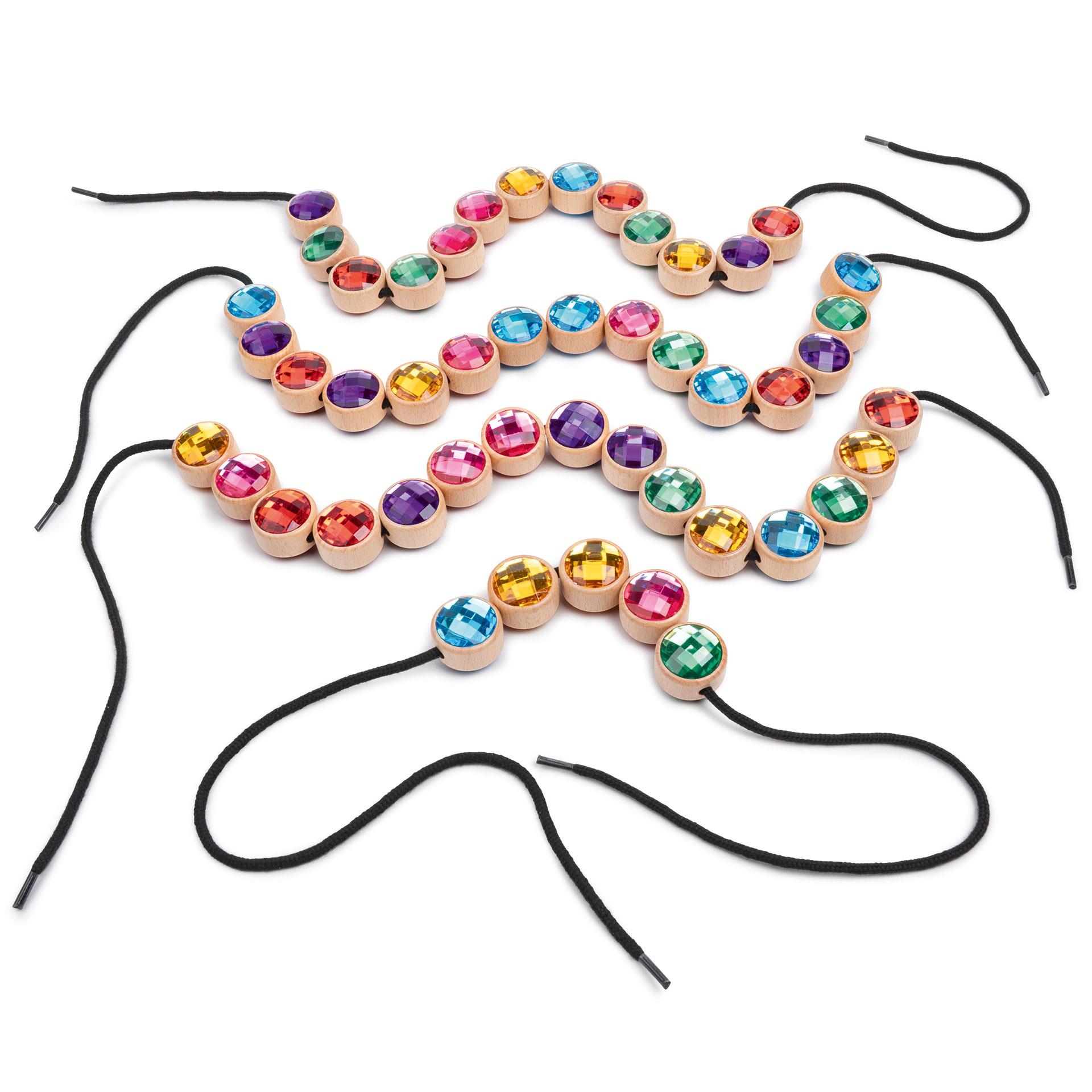 Bunte runde Holz Schmucksteine mit glitzernder Oberfläche, dazu schwarze Fäden und ein weisser Stoffsack