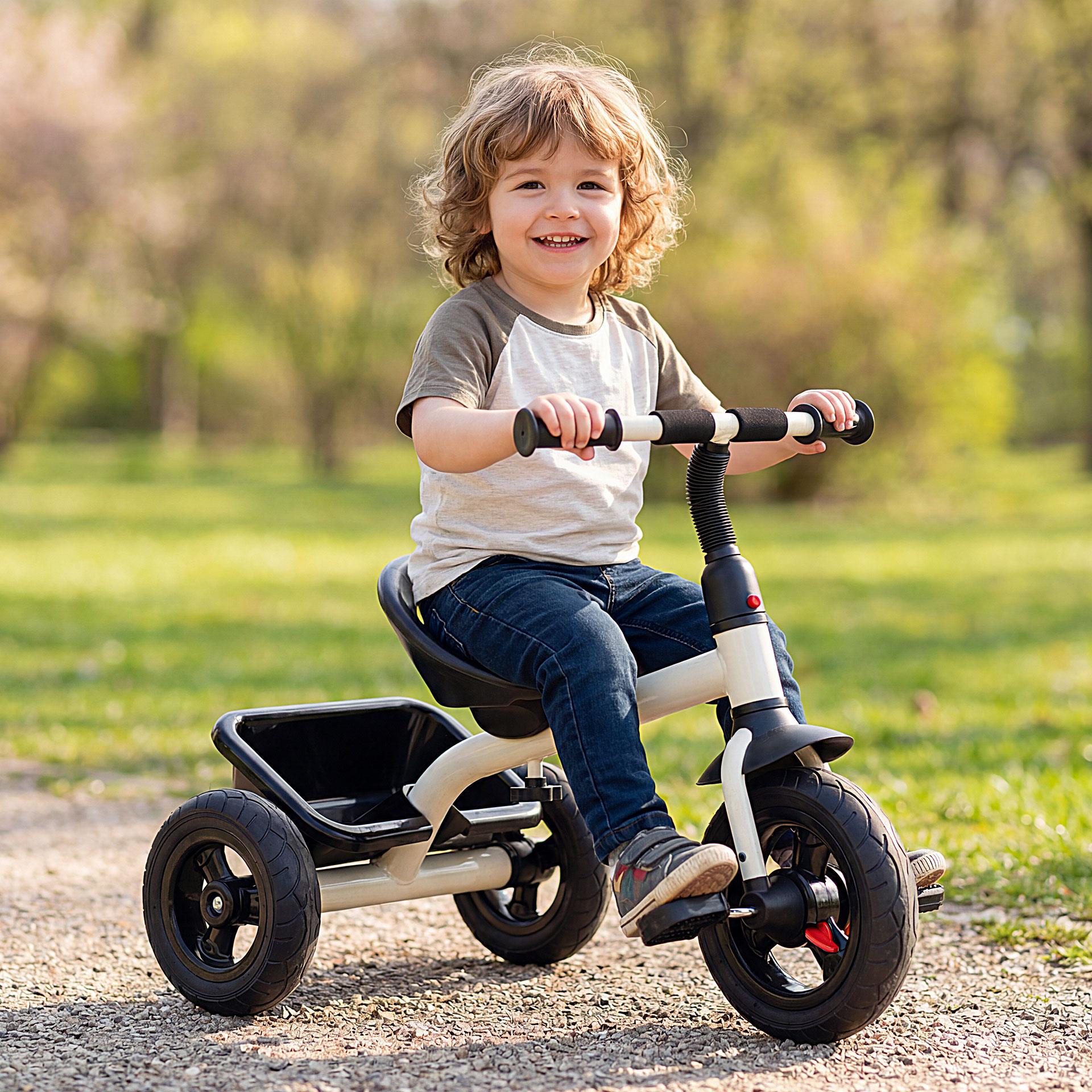 Ein modernes, weissschwarzes Dreirad für Kinder mit stabilen Gummireifen und einem praktischen Transportkorb hinten