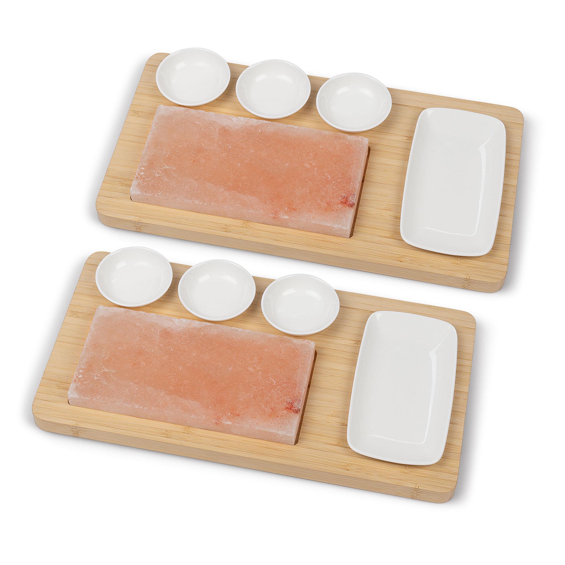 Zwei Bambus-Servierbretter mit roten Himalaya-Salzsteinen, je drei weissen Keramikschälchen und einem weissen Keramikteller