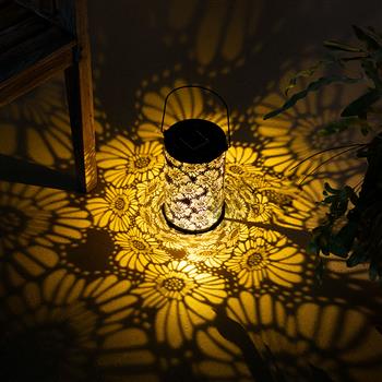 Una lanterna solare cilindrica con motivo floreale traforato e un sottile manico in metallo per appenderla