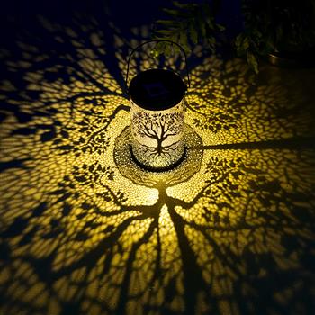 Eine zylindrische Solarlaterne mit einem kunstvoll ausgestanzten Baum-des-Lebens-Motiv und einem Metallhenkel zum Aufhängen